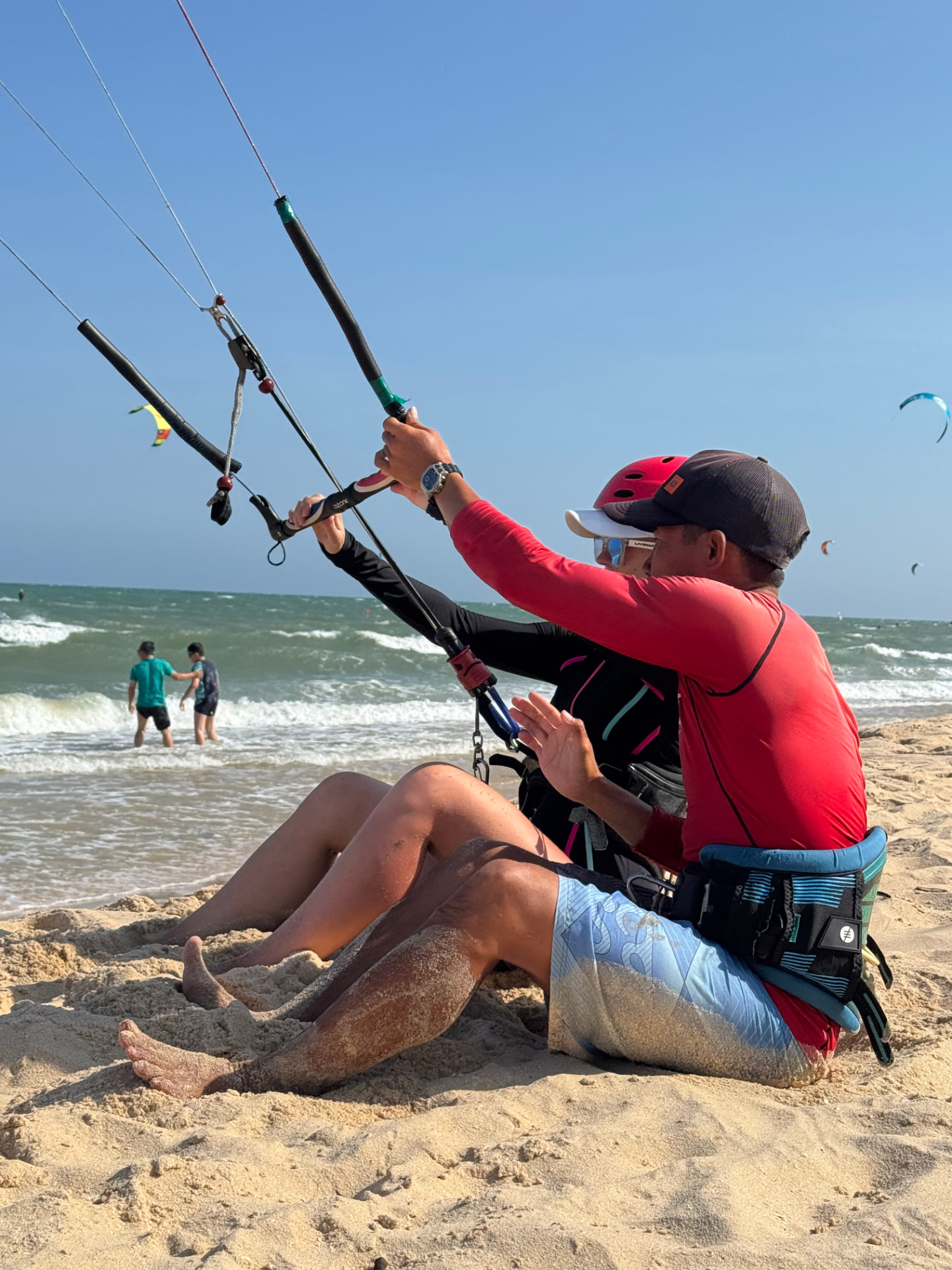 Lý teaching bar control to a student sitting on the beach