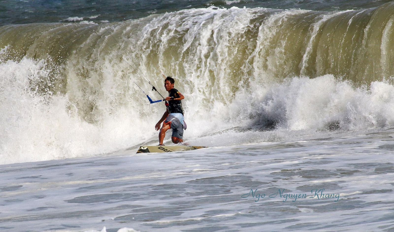 Kitesurfer riding in front of a breaking wave in Mui Ne