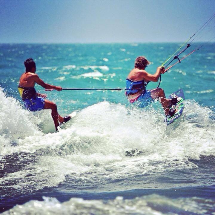 Two kitesurfers carving through waves side by side in Mui Ne