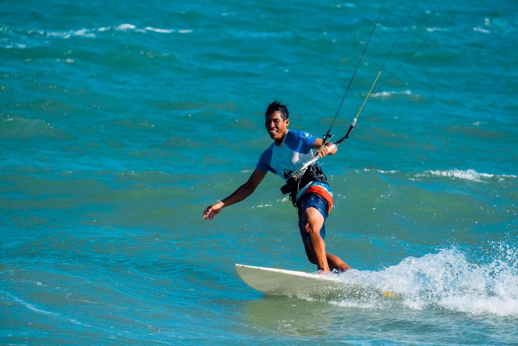 Lý smiling while kitesurfing on a wave in Mui Ne