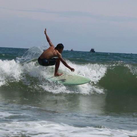 Lý carving a wave on his surfboard at Ham Tien beach